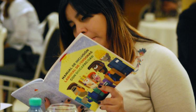 Participante del Desayuno leyendo el Manual de Inclusión Laboral de Personas con Discapacidad.