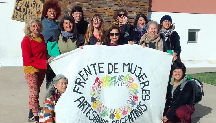 Mujeres en grupo con una bandera por delante que dice Frente de mujeres artesanas